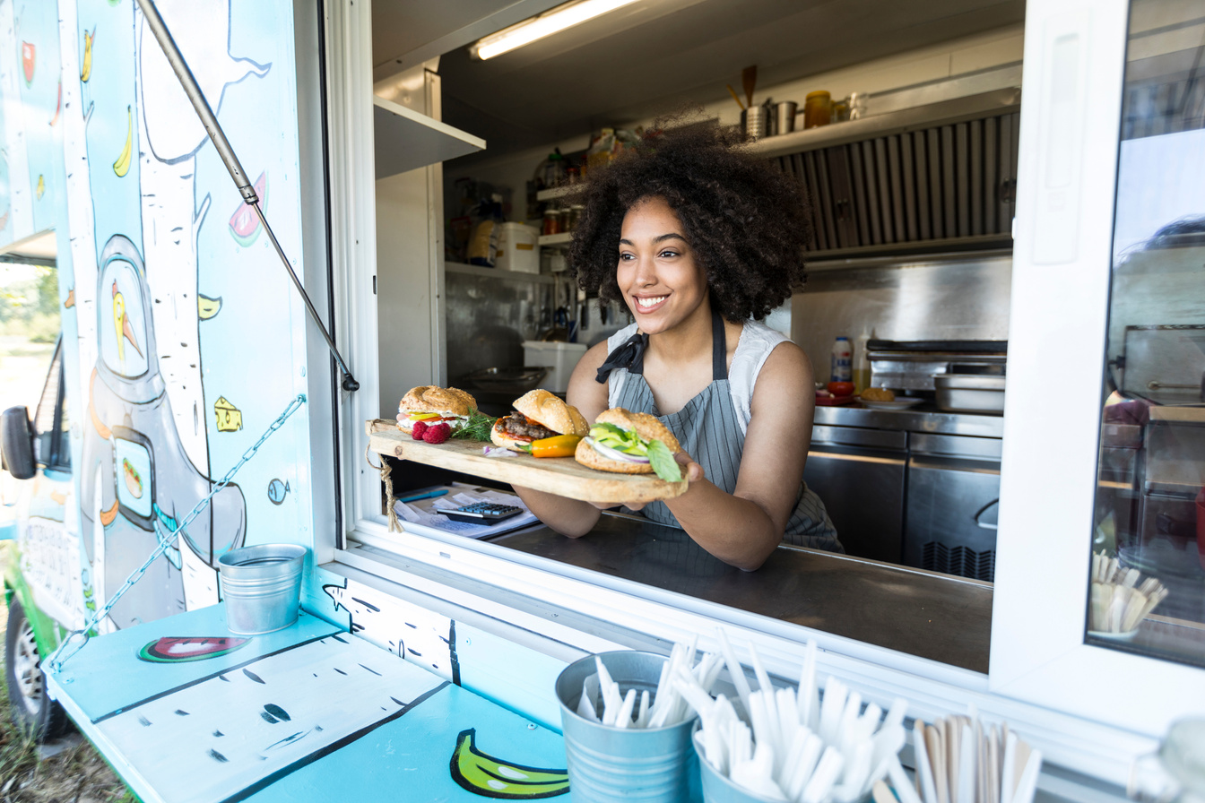 Female food vendor offering sandwiches in food van